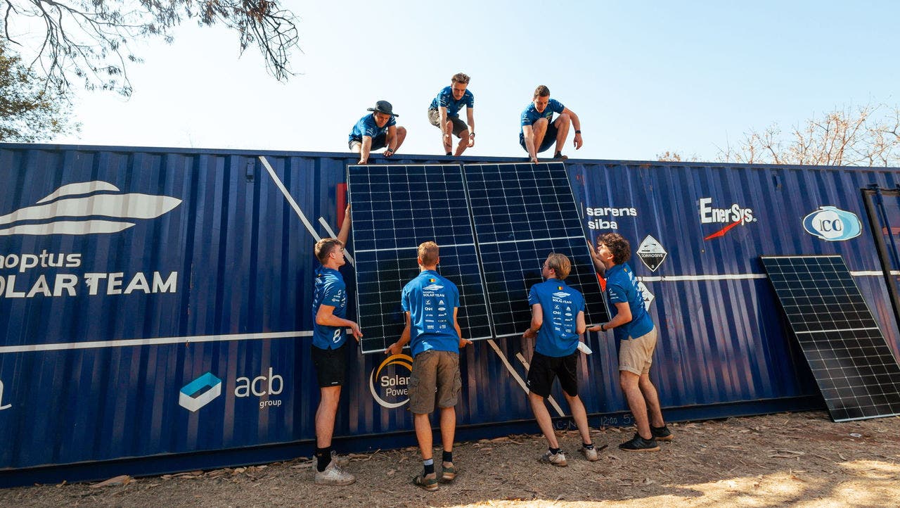 Student team installing a solar panel on top of a workshop container.