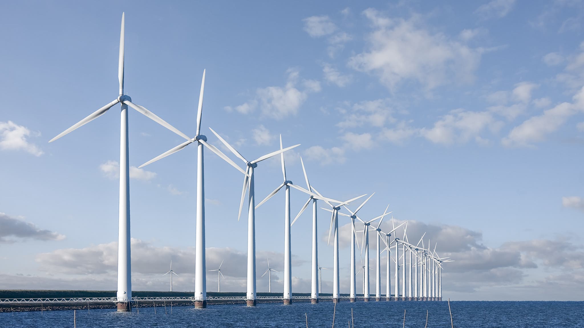 Enormous windmills standing in the sea along a Dutch sea barrier