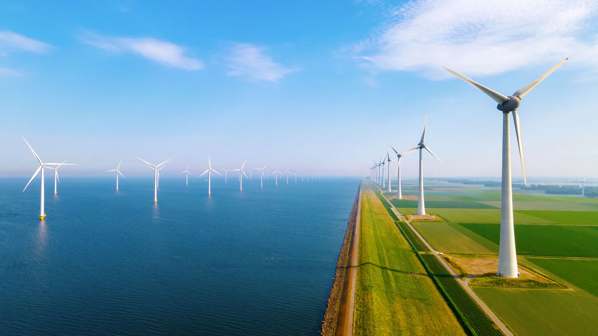 Renewable Energy Wind Power Wind turbines along coastal landscape with green fields and blue sky