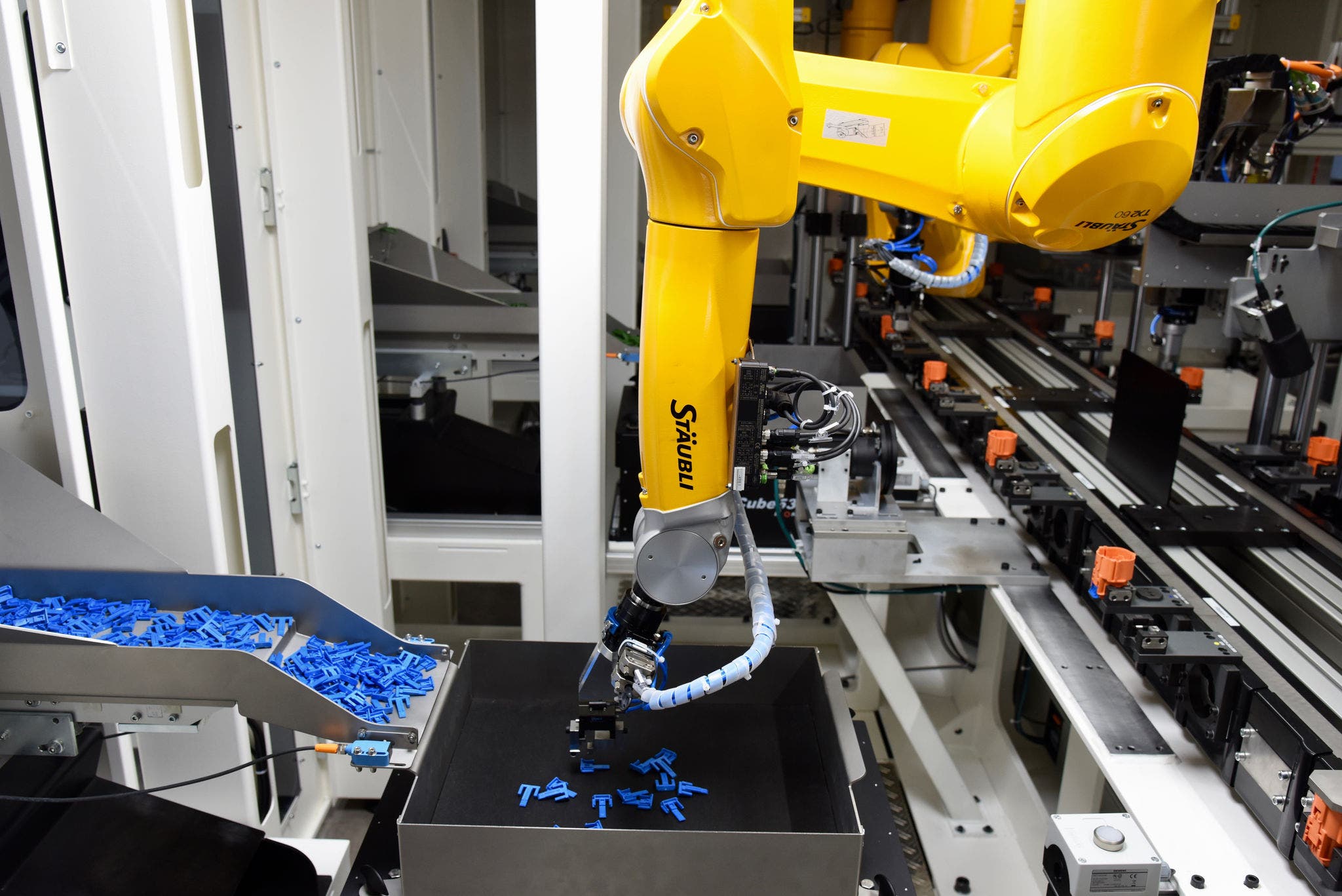 The second Stäubli six-axis robot picks up a connector lock from a vibration platform and attaches it to the connector housing.