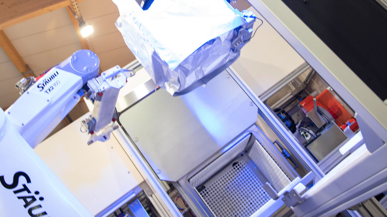 Robot presents the packaged box to a vision system for quality control