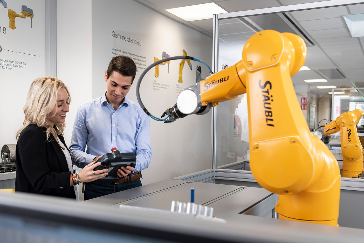 Students in front of a teaching robot, a SP2 teach pendant in the hands.