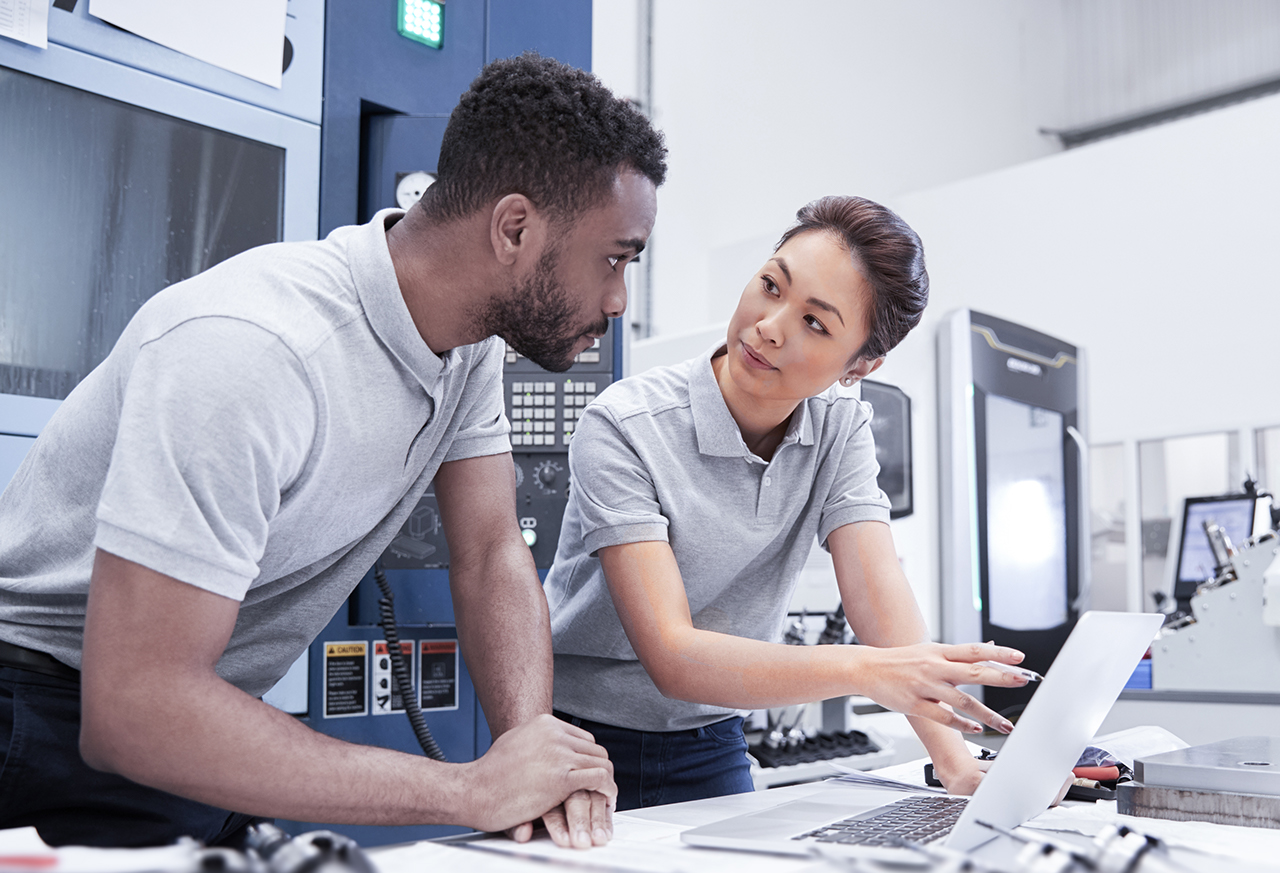 Two Engineers Using CAD Programming Software On Laptop